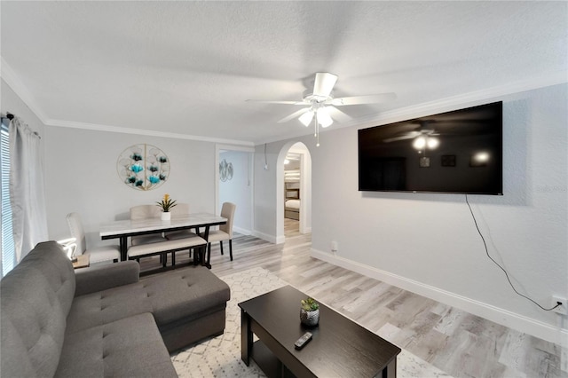 living room featuring ceiling fan, light hardwood / wood-style flooring, ornamental molding, and a textured ceiling