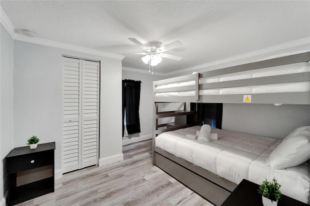 bedroom featuring ceiling fan, ornamental molding, light hardwood / wood-style floors, a textured ceiling, and a closet