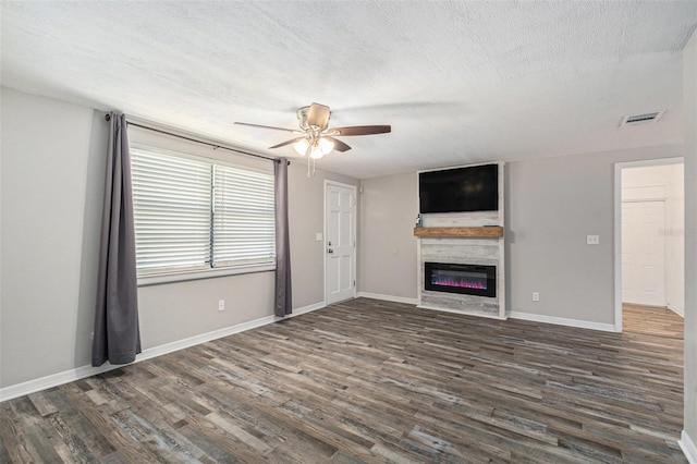 unfurnished living room with a textured ceiling, dark hardwood / wood-style floors, and ceiling fan