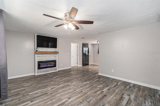 unfurnished living room featuring dark wood-type flooring, ceiling fan, a fireplace, and a textured ceiling