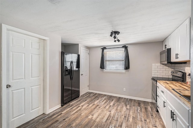 kitchen featuring butcher block countertops, black appliances, dark hardwood / wood-style flooring, decorative backsplash, and white cabinets