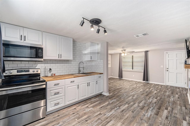 kitchen with butcher block counters, sink, white cabinets, decorative backsplash, and stainless steel appliances