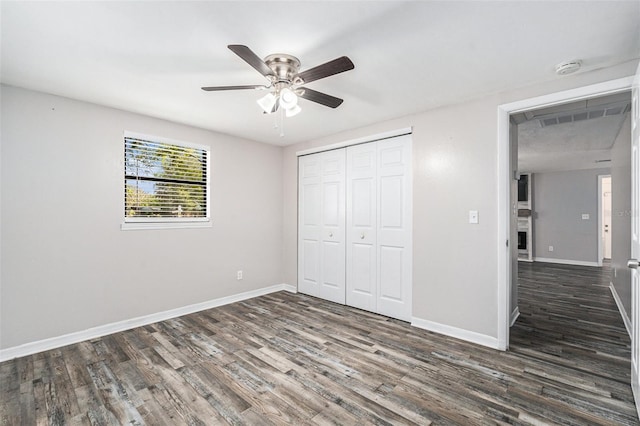 unfurnished bedroom featuring ceiling fan, dark hardwood / wood-style flooring, and a closet