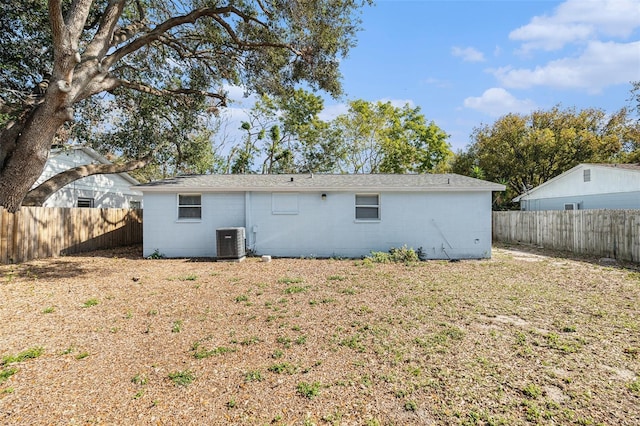 back of property featuring central AC unit and a lawn