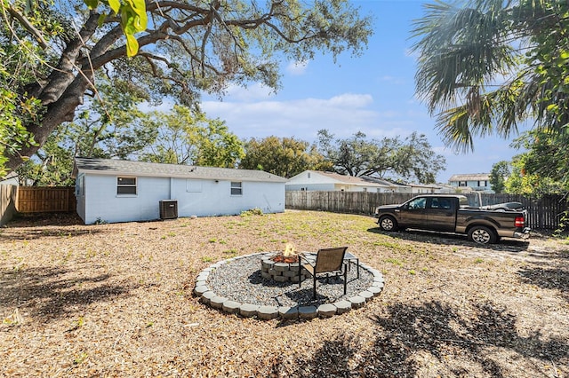 view of yard with central air condition unit and an outdoor fire pit