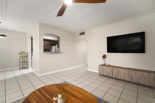 unfurnished living room with ceiling fan, light tile patterned floors, and a textured ceiling