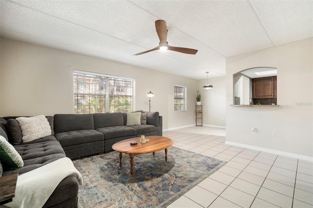 living room featuring a textured ceiling, ceiling fan, and light tile patterned flooring