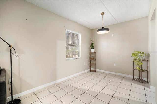 tiled empty room featuring a textured ceiling