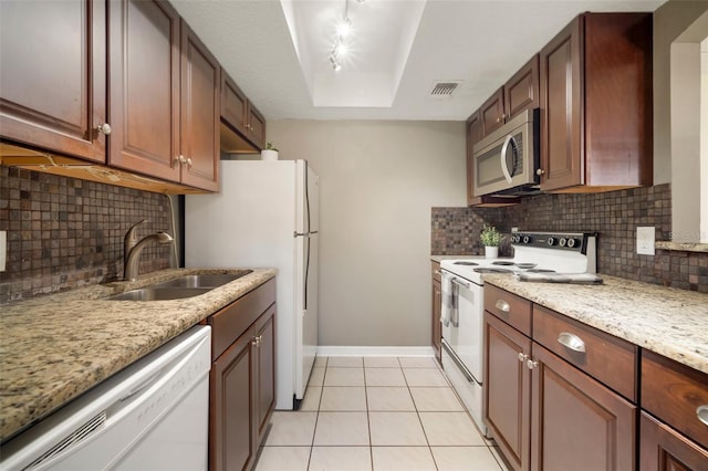 kitchen with sink, white appliances, light tile patterned floors, light stone counters, and a raised ceiling