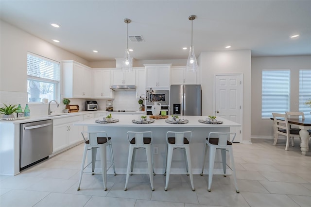 kitchen with stainless steel appliances, white cabinetry, and a kitchen island