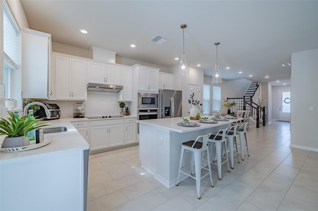 kitchen featuring stainless steel appliances, a center island, sink, and white cabinets