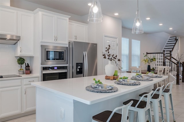 kitchen featuring tasteful backsplash, a kitchen island, white cabinets, and appliances with stainless steel finishes