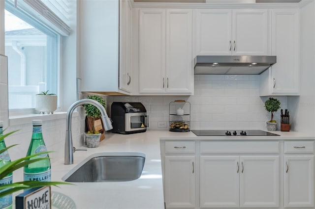 kitchen featuring white cabinetry, black electric stovetop, sink, and backsplash