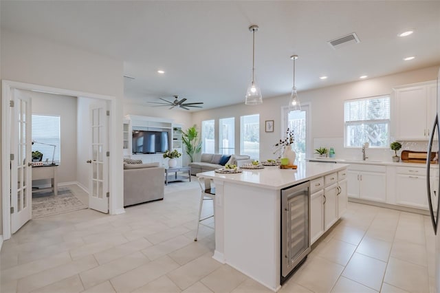 kitchen with white cabinets, tasteful backsplash, a kitchen island, and wine cooler