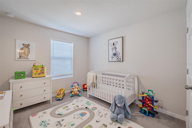 carpeted bedroom featuring a nursery area