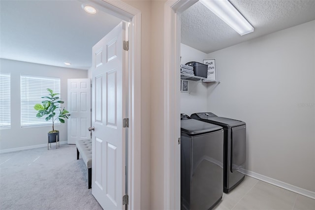 laundry area with independent washer and dryer, light carpet, and a textured ceiling