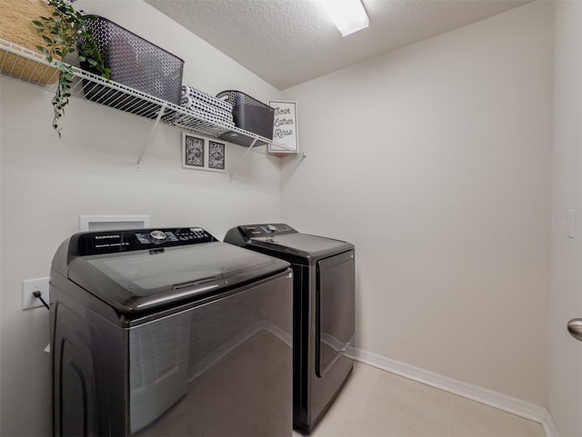 laundry room with separate washer and dryer, light tile patterned floors, and a textured ceiling