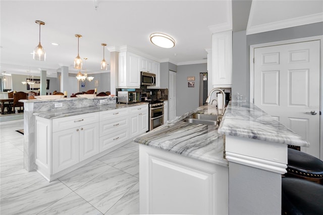 kitchen with sink, appliances with stainless steel finishes, hanging light fixtures, kitchen peninsula, and a chandelier