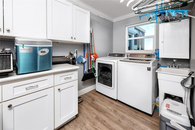 clothes washing area with cabinets, ornamental molding, washer and dryer, and light wood-type flooring