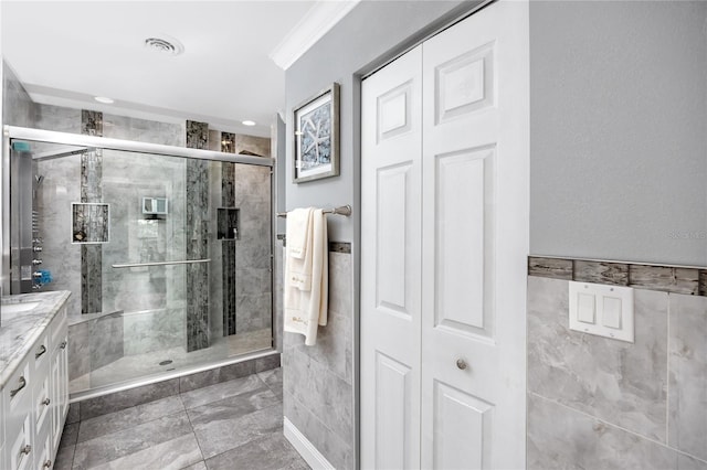 bathroom with a shower with door, vanity, and crown molding