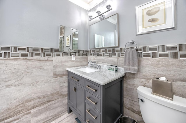 bathroom with vanity, toilet, and tile walls