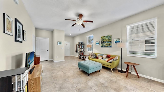 living area with ceiling fan, baseboards, and light tile patterned floors