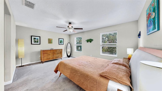 carpeted bedroom with visible vents, baseboards, and a ceiling fan