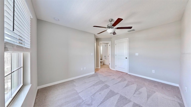 unfurnished room featuring ceiling fan, light colored carpet, baseboards, and visible vents
