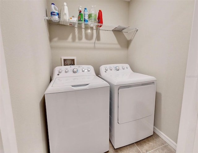 laundry room with washing machine and clothes dryer, light tile patterned floors, baseboards, and laundry area