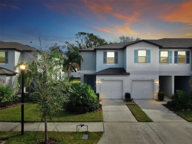 multi unit property featuring concrete driveway, a shingled roof, stucco siding, and a garage