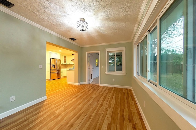 interior space featuring ornamental molding, a textured ceiling, and light wood-type flooring