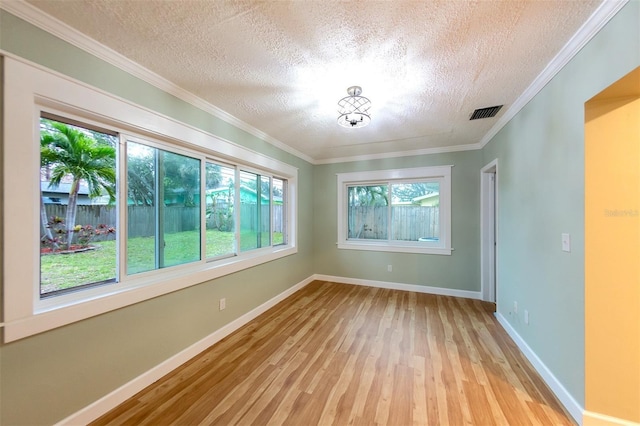 unfurnished room featuring crown molding, light hardwood / wood-style flooring, and a textured ceiling