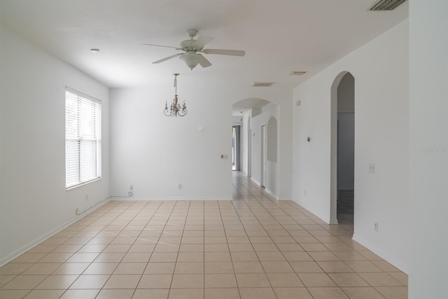 tiled spare room featuring ceiling fan with notable chandelier