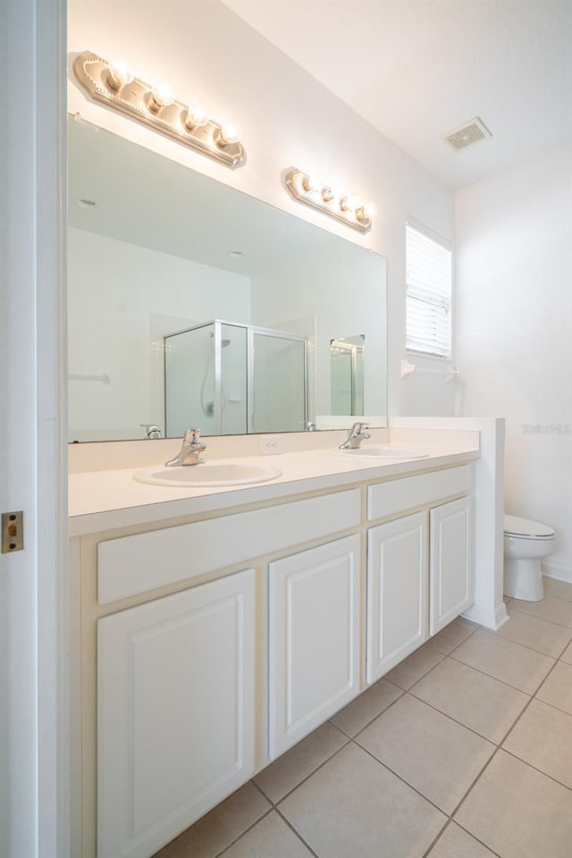 bathroom featuring tile patterned flooring, vanity, toilet, and walk in shower