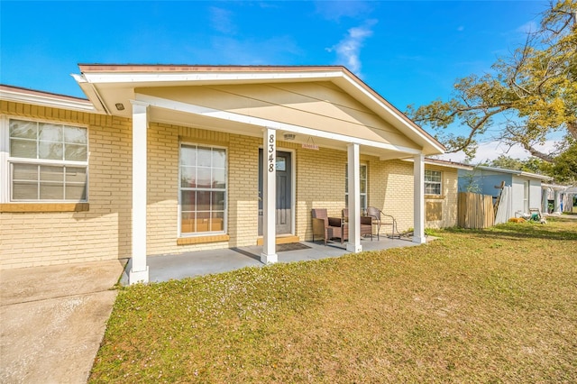 back of property with a yard and covered porch