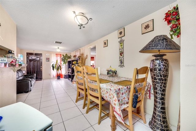 dining space featuring light tile patterned flooring and a textured ceiling