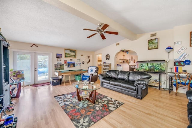 living room with hardwood / wood-style floors, vaulted ceiling with beams, ceiling fan, a textured ceiling, and french doors