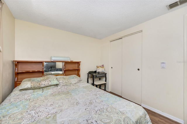 bedroom with hardwood / wood-style flooring, a textured ceiling, and a closet