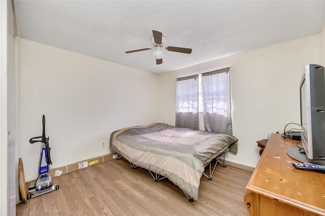 bedroom with ceiling fan, a textured ceiling, and light wood-type flooring