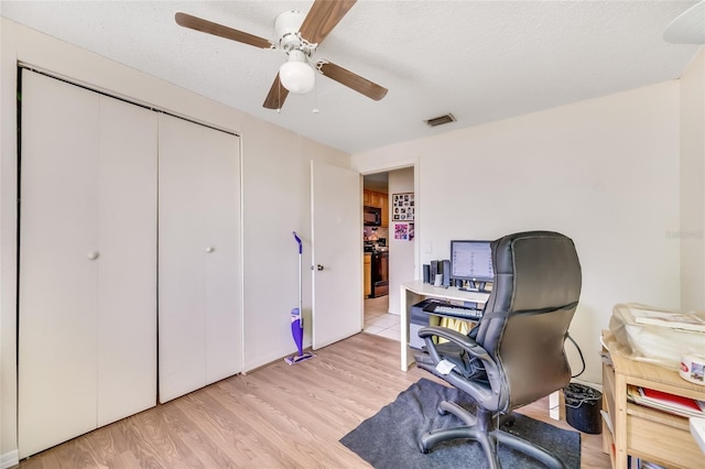 home office featuring ceiling fan, light hardwood / wood-style floors, and a textured ceiling