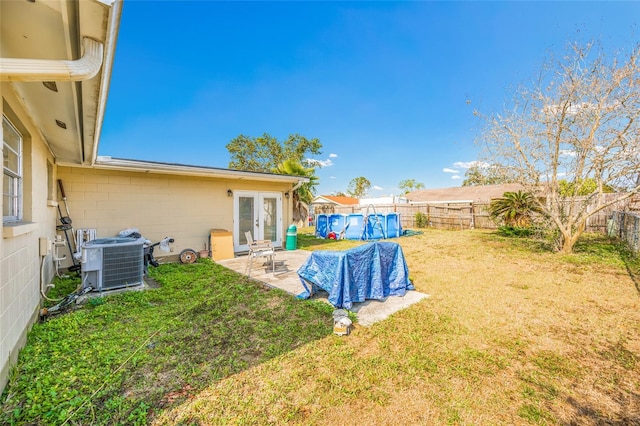 view of yard featuring a patio area, a swimming pool, central AC unit, and french doors