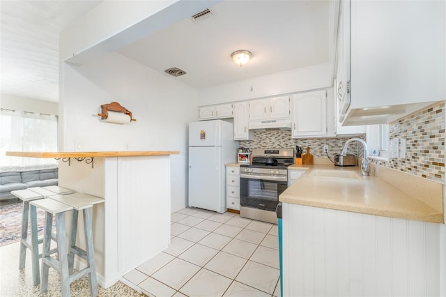 kitchen with a kitchen bar, sink, white cabinetry, white refrigerator, and electric stove