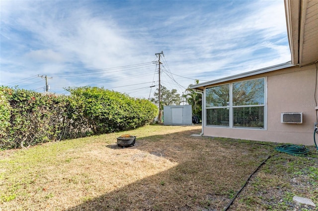 view of yard with a storage shed, a wall mounted AC, and a fire pit