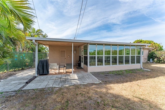 rear view of house featuring a sunroom and a patio