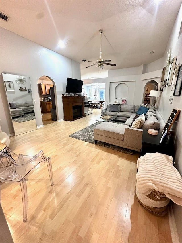 living room with ceiling fan, hardwood / wood-style floors, a textured ceiling, and a fireplace