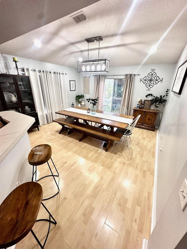 dining room with hardwood / wood-style floors and a textured ceiling