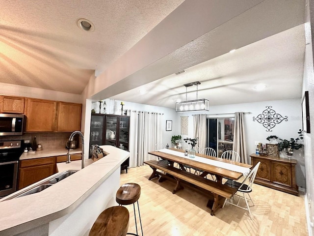 kitchen with sink, light hardwood / wood-style flooring, hanging light fixtures, electric range oven, and decorative backsplash