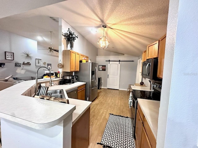 kitchen with appliances with stainless steel finishes, pendant lighting, kitchen peninsula, a barn door, and a textured ceiling