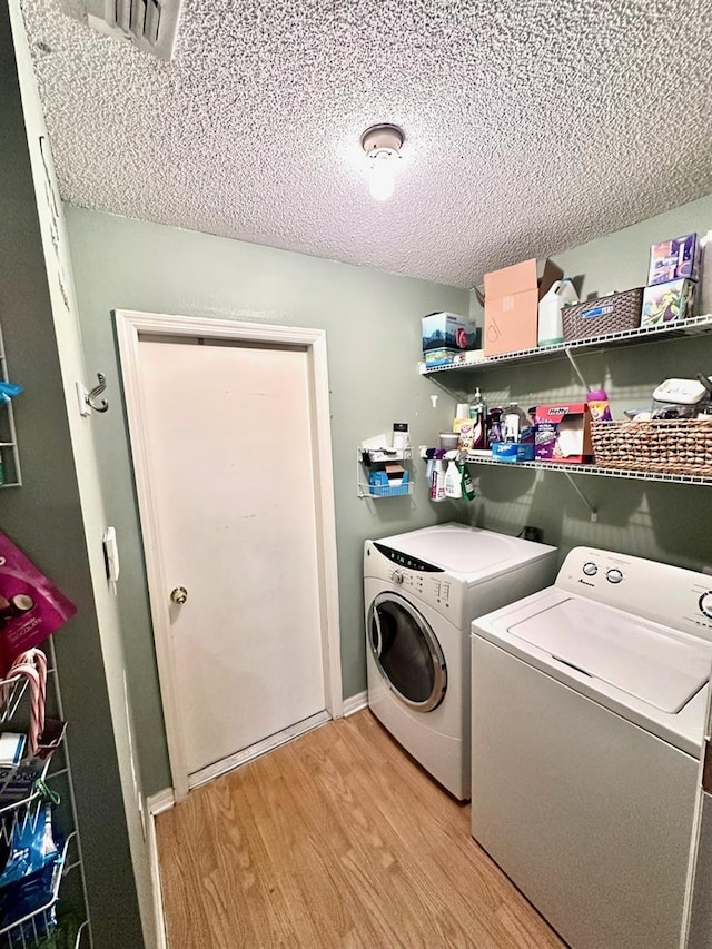 laundry area with independent washer and dryer, light hardwood / wood-style floors, and a textured ceiling