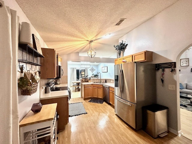 kitchen featuring appliances with stainless steel finishes, decorative light fixtures, sink, kitchen peninsula, and a textured ceiling